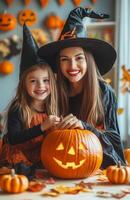 A mother and daughter sit at a table decorating a pumpkin for Halloween in festive costumes photo