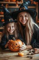 A mother and daughter sit at a table decorating a pumpkin for Halloween in festive costumes photo