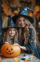 A mother and daughter sit at a table decorating a pumpkin for Halloween in festive costumes photo