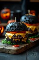 Halloween monster themed burgers with black buns, cheese, and ketchup on a wooden board photo