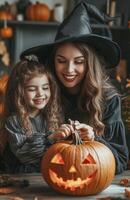 A mother and daughter sit at a table decorating a pumpkin for Halloween in festive costumes photo