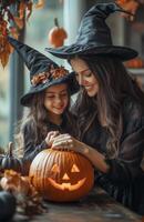 A mother and daughter sit at a table decorating a pumpkin for Halloween in festive costumes photo