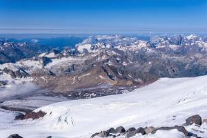 top view of the high mountains above the clouds from the glacier on the slope of Mount Elbrus photo