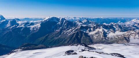 panoramic view of the high mountains above the clouds from the snowy slope of Mount Elbrus photo