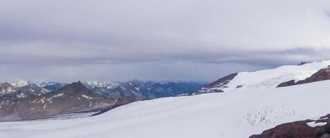 high mountain glacier in cloudy weather with distant mountains in the background photo