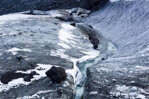 streams of water on the surface of a melting high-mountain glacier photo