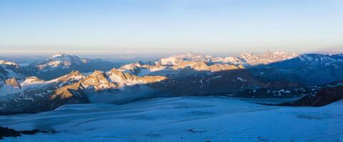 dawn panoramic view of the high mountains above the clouds from the glacier on the slope of Mount Elbrus photo