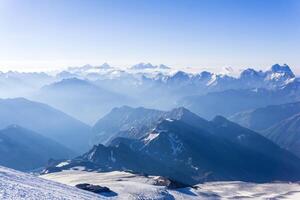 view from highland snowy slope to misty mountains in the rays of dawn photo