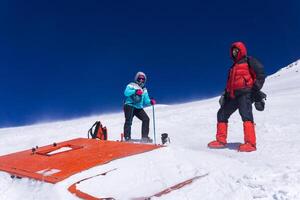 Climbers stand at an altitude of 5,000 meters above sea level near a broken snowcat that sank into a glacier photo