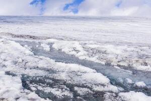 streams of water on the surface of a melting high-mountain glacier photo