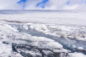 streams of water on the surface of a melting high-mountain glacier photo