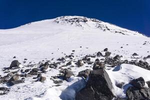 snowy mountain landscape with dark highland sky, view of the eastern peak of Mount Elbrus from a snowfield near Pastukhov Rocks photo