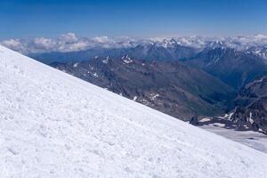 mountain landscape, view from highland icefield on slope to mountain ranges in the clouds, view from the Mount Elbrus to the Main Caucasian Range photo