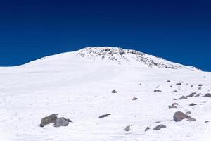 snowy mountain landscape with dark highland sky, view of the eastern peak of Mount Elbrus from a snowfield near Pastukhov Rocks photo