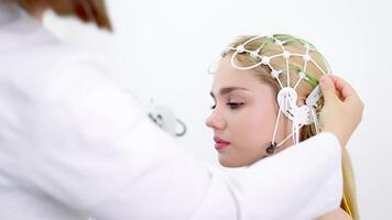 A doctor places EEG sensors on a young patient's head for brain testing in a medical center. Ideal for showcasing advanced diagnostics and professional healthcare settings video