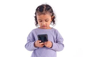 A little Asian girl with a serious face looking at her mobile phone, on a white background photo