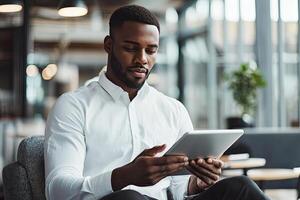 Close up of young businessman using digital tablet while sitting at his working place in office. Businessman using digital tablet photo