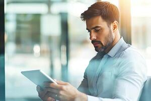Close up of young businessman using digital tablet while sitting at his working place in office. Businessman using digital tablet photo