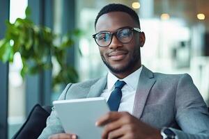 Close up of young businessman using digital tablet while sitting at his working place in office. Businessman using digital tablet photo