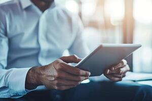 Close up of young businessman using digital tablet while sitting at his working place in office. Businessman using digital tablet photo