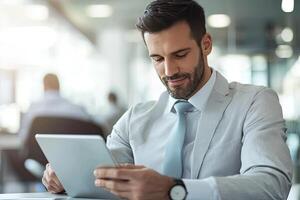 Close up of young businessman using digital tablet while sitting at his working place in office. Businessman using digital tablet photo