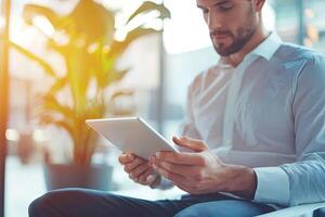 Close up of young businessman using digital tablet while sitting at his working place in office. Businessman using digital tablet photo