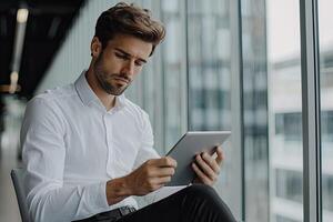 Close up of young businessman using digital tablet while sitting at his working place in office. Businessman using digital tablet photo