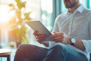 Close up of young businessman using digital tablet while sitting at his working place in office. Businessman using digital tablet photo