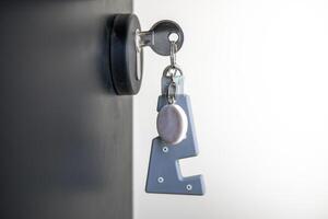 A house key with a key ring inserted at the door lock. Buy new home or concept photo