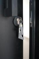 A house key with a key ring inserted at the door lock. Buy new home or concept photo