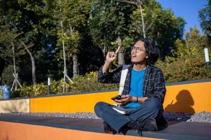 A man wearing a plaid shirt sitting in the park makes an expression of getting an idea. photo