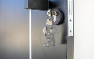 A house key with a key ring inserted at the door lock. Buy new home or concept photo
