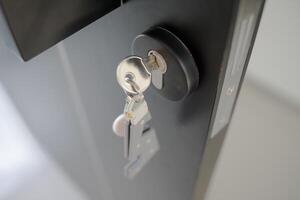 A house key with a key ring inserted at the door lock. Buy new home or concept photo