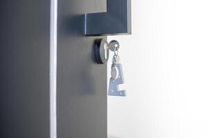 A house key with a key ring inserted at the door lock. Buy new home or concept photo