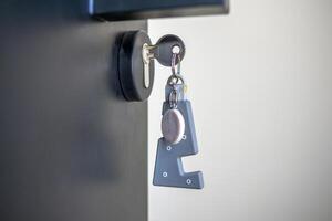A house key with a key ring inserted at the door lock. Buy new home or concept photo