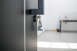 A house key with a key ring inserted at the door lock. Buy new home or concept photo