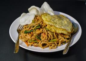 Fried noodles are one of the most popular foods in Southeast Asia, including Indonesia. Served with eggs and vegetables, on a plate photo