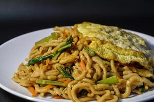 Fried noodles are one of the most popular foods in Southeast Asia, including Indonesia. Served with eggs and vegetables, on a plate photo