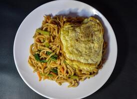 Fried noodles are one of the most popular foods in Southeast Asia, including Indonesia. Served with eggs and vegetables, on a plate photo