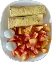 This plate features chopped chicken wrapped in lavash, served with boiled eggs and vibrant red tomatoes. A nutritious meal combining protein-rich elements with fresh, juicy tomatoes. photo