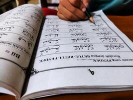 Bekonang, Sukoharjo, March 26, 2023. Islamic student is learning basic reading verses of the Quran by using the Iqra ', which is quick and clever methods at Islamic primary school. photo