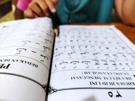 Bekonang, Sukoharjo, March 26, 2023. Islamic student is learning basic reading verses of the Quran by using the Iqra ', which is quick and clever methods at Islamic primary school. photo