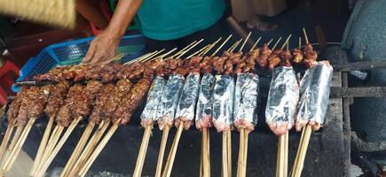 Defocused of Sate Buntel or Satay Buntel is satay made from minced mutton wrapped in mutton fat is being grilled on charcoal photo