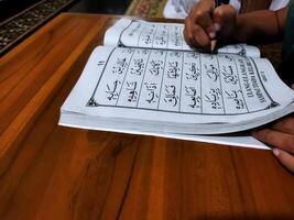 Bekonang, Sukoharjo, March 26, 2023. Islamic student is learning basic reading verses of the Quran by using the Iqra ', which is quick and clever methods at Islamic primary school. photo