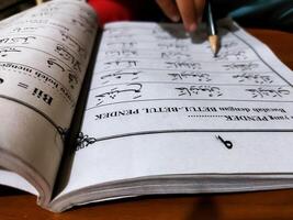 Bekonang, Sukoharjo, March 26, 2023. Islamic student is learning basic reading verses of the Quran by using the Iqra ', which is quick and clever methods at Islamic primary school. photo