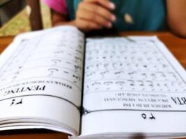 Bekonang, Sukoharjo, March 26, 2023. Islamic student is learning basic reading verses of the Quran by using the Iqra ', which is quick and clever methods at Islamic primary school. photo