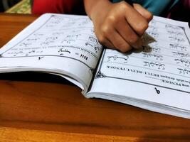 Bekonang, Sukoharjo, March 26, 2023. Islamic student is learning basic reading verses of the Quran by using the Iqra ', which is quick and clever methods at Islamic primary school. photo