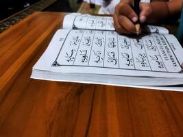 Bekonang, Sukoharjo, March 26, 2023. Islamic student is learning basic reading verses of the Quran by using the Iqra ', which is quick and clever methods at Islamic primary school. photo