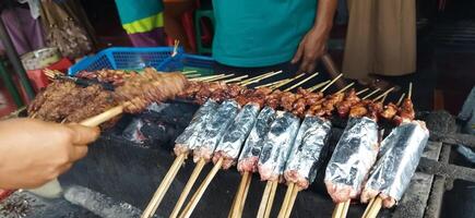 Defocused of Sate Buntel or Satay Buntel is satay made from minced mutton wrapped in mutton fat is being grilled on charcoal photo