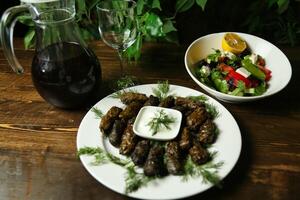 Stuffed Grape Leaves With Salad and Wine on Wooden Table photo
